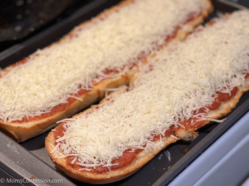 french bread on a baking sheet with pizza sauce and mozzarella cheese