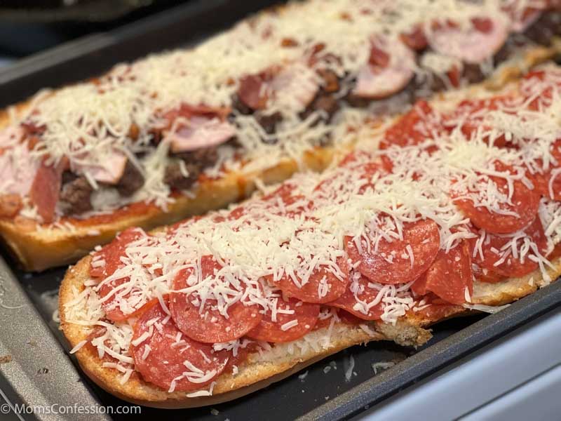 close up of meat lovers and pepperoni french bread pizza on a baking sheet