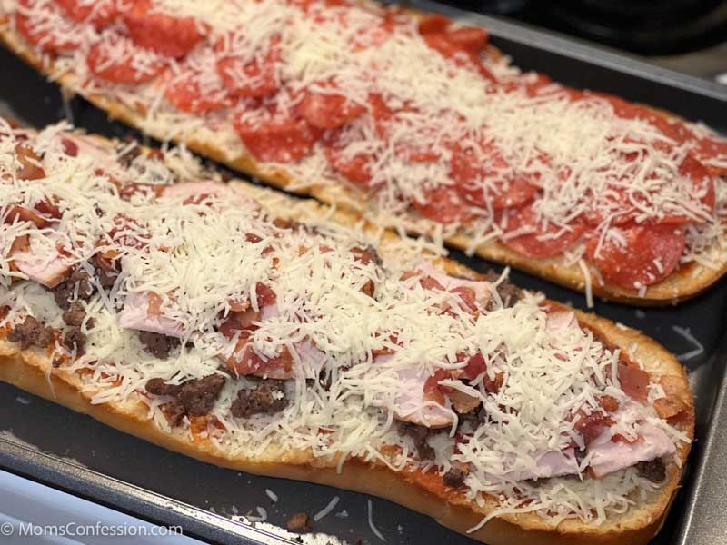 close up of meat lovers and pepperoni french bread pizza on a baking sheet