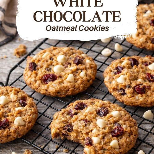 Chewy oatmeal cookies filled with dried cranberries and white chocolate chips cooling on a wire rack.