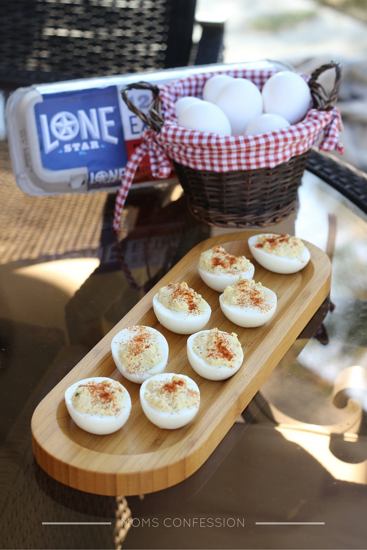 deviled eggs placed on a brown platter with eggs in the background