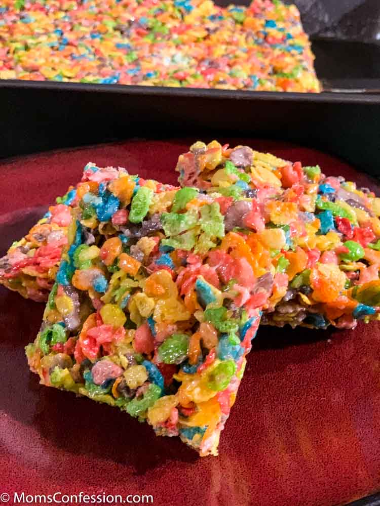 Fruity Pebble Rice Crispy Treats cut into squares on a red plate