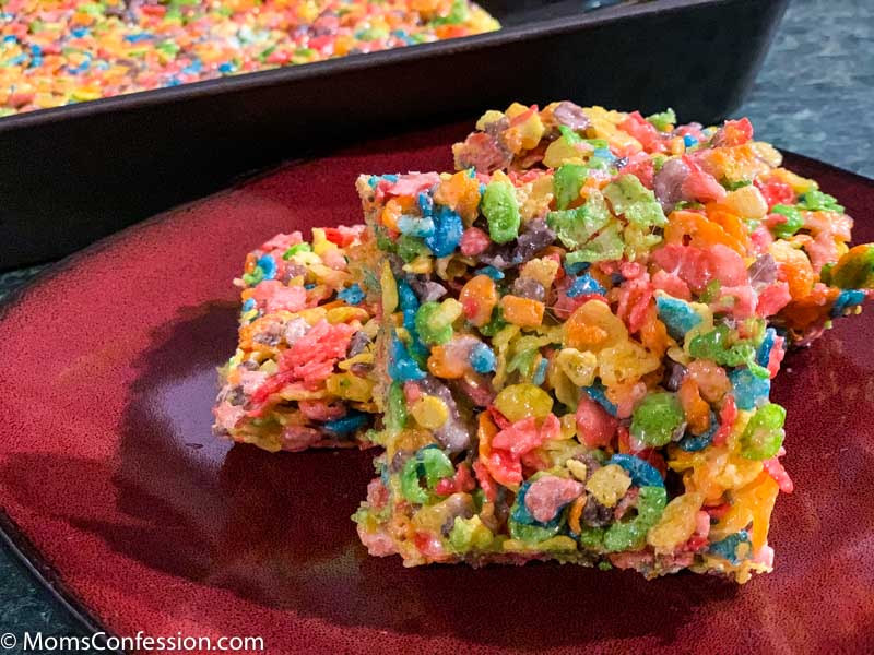 Fruity Pebble Rice Crispy Treats cut into squares on a red plate