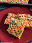 Fruity Pebble Rice Crispy Treats cut into squares on a red plate