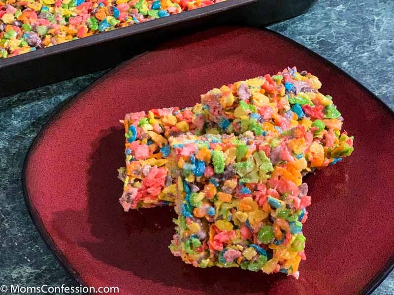 Fruity Pebble Rice Crispy Treats cut into squares on a red plate