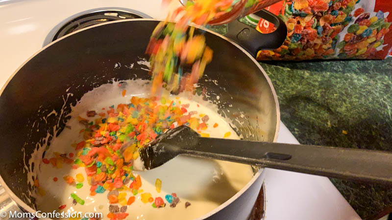 mixing fruity pebbles cereal with marshmallows on the stove