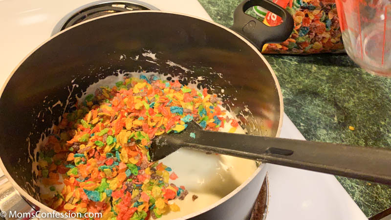 mixing fruity pebbles cereal with marshmallows on the stove