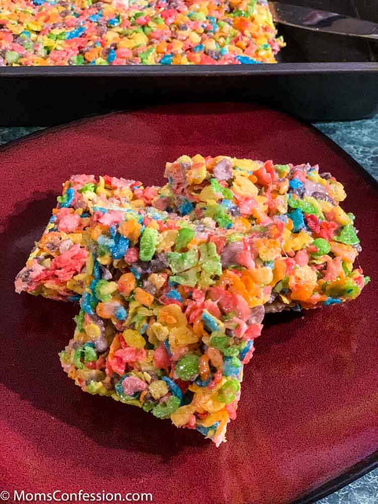 Fruity Pebble Rice Crispy Treats cut into squares on a red plate