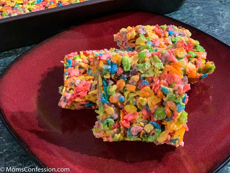 Fruity Pebble Rice Crispy Treats cut into squares on a red plate