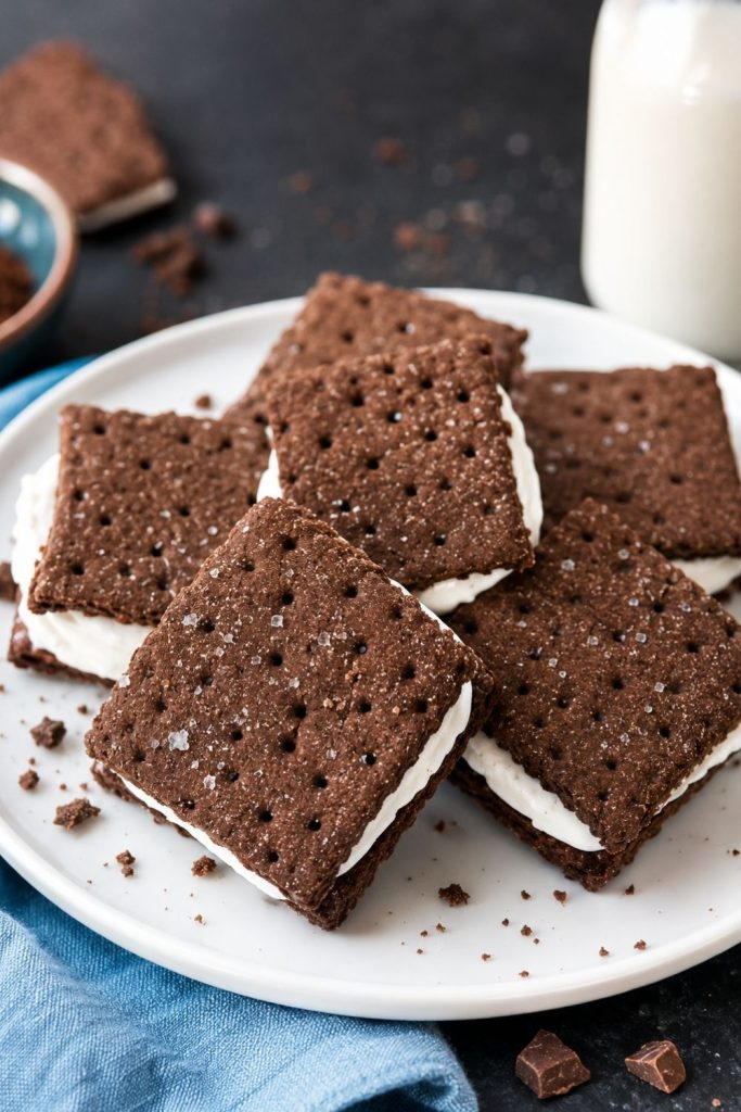 Chocolate graham cracker sandwiches filled with creamy vanilla filling served on a white plate for an easy summer snack.