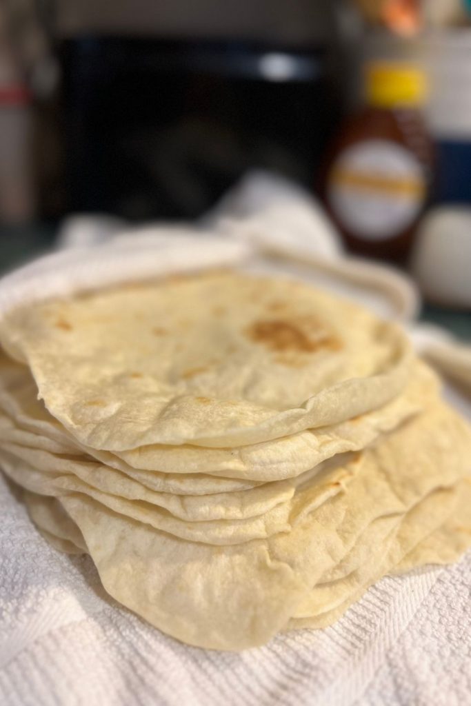 Stack of soft homemade flour tortillas made from scratch with simple pantry ingredients.